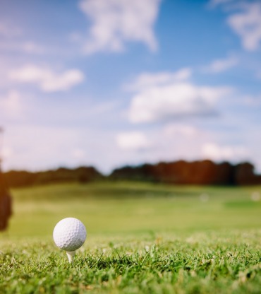 White golf ball on a green grass. Golf course. Summer luxury activities.